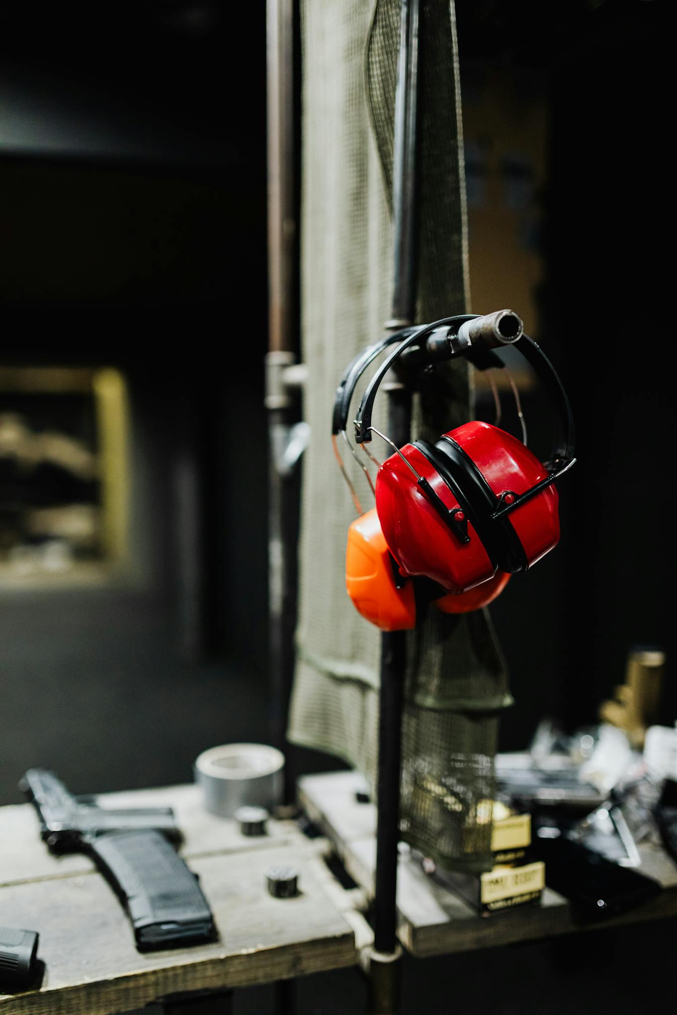 Red earmuffs on display at an indoor shooting range, emphasizing safety gear importance.